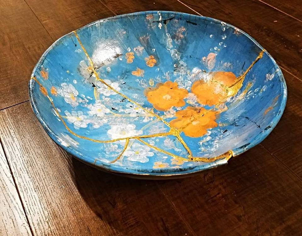 Blue bowl with orange flowers with cracks repaired with gold in Kintsugi style