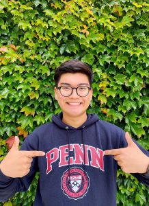 Man pointing at Penn logo on sweatshirt smiling