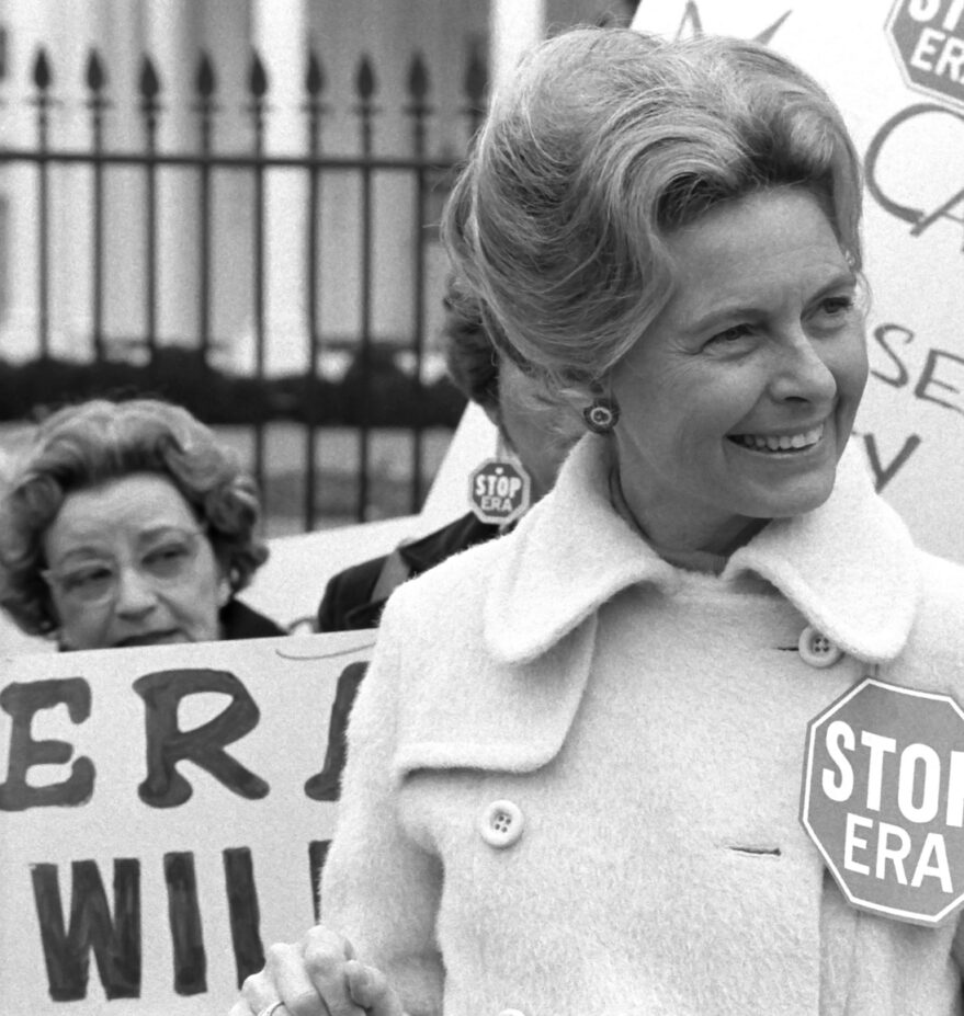 This is an image of activist Phyllis Schafly with women behind her holding picket signs.