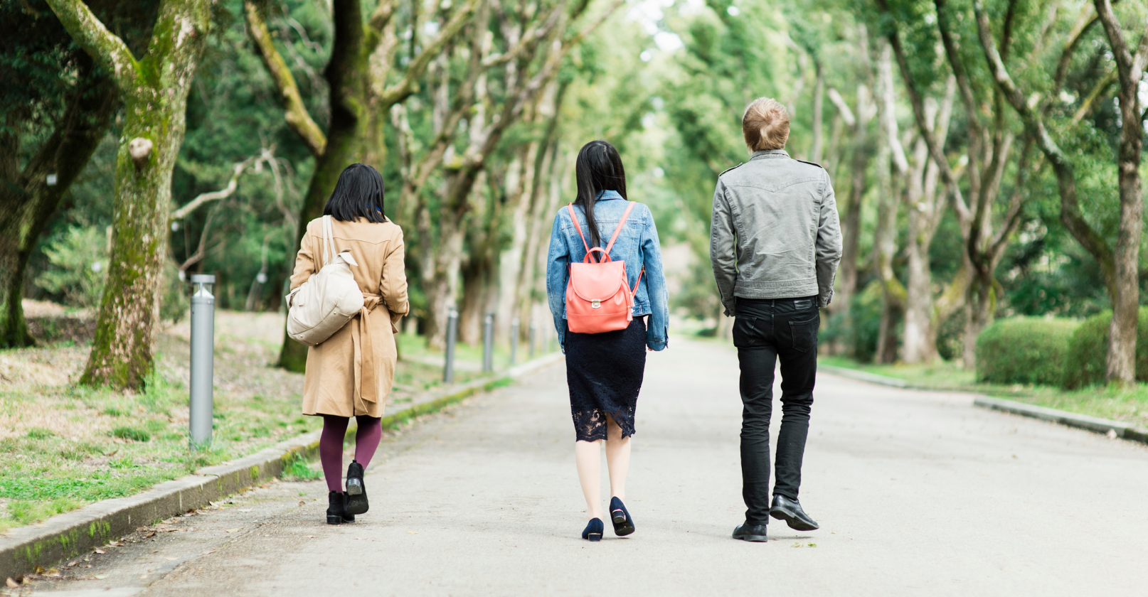 three college age people stroll down road