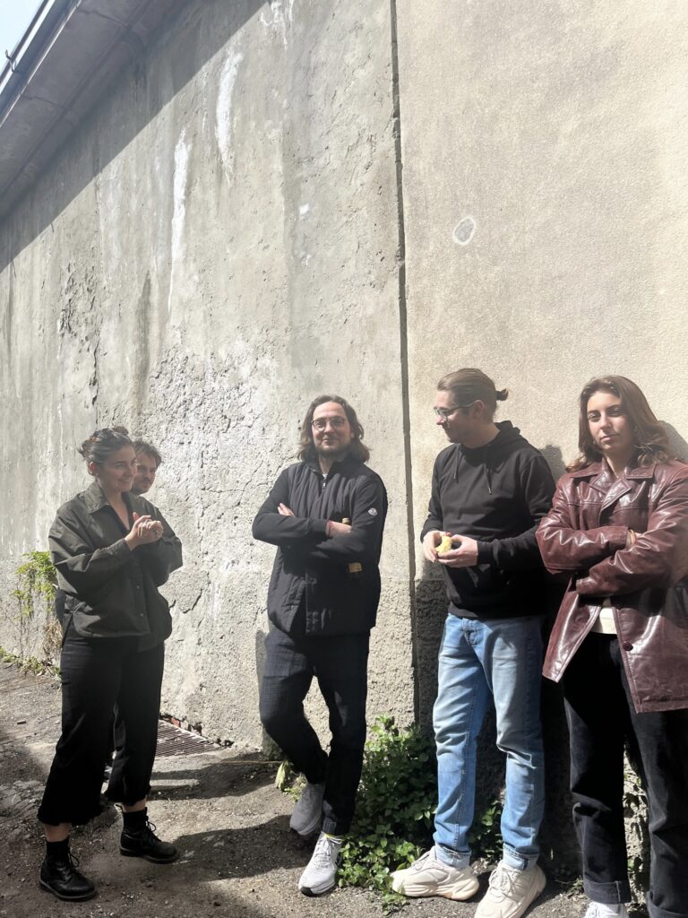 group of people standing outside against concrete wall