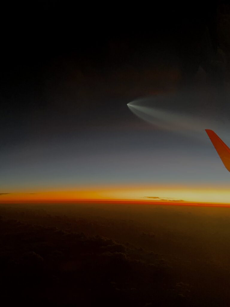 Sunset view from airplane window with jet engine visible again a dark gray and orange sky