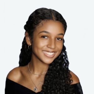 Headshot of woman with long curly black hair smiling at camera wearing an off the shoulder black top