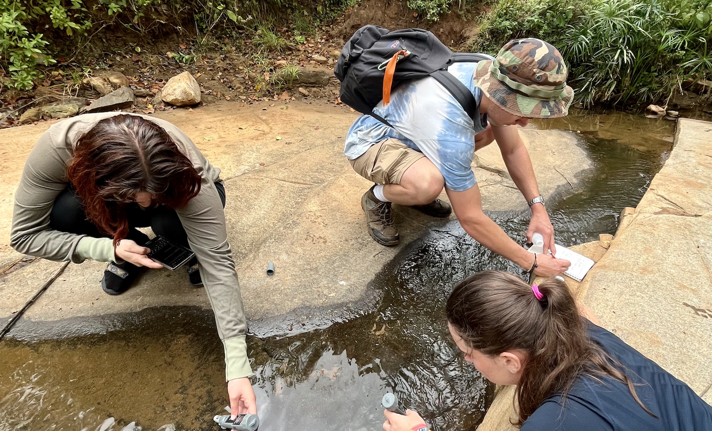 three student researchers testing the waters by collecting samples in Kenya