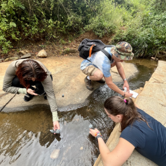 three student researchers testing the waters by collecting samples in Kenya