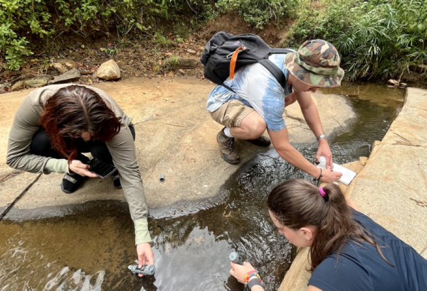 three student researchers testing the waters by collecting samples in Kenya