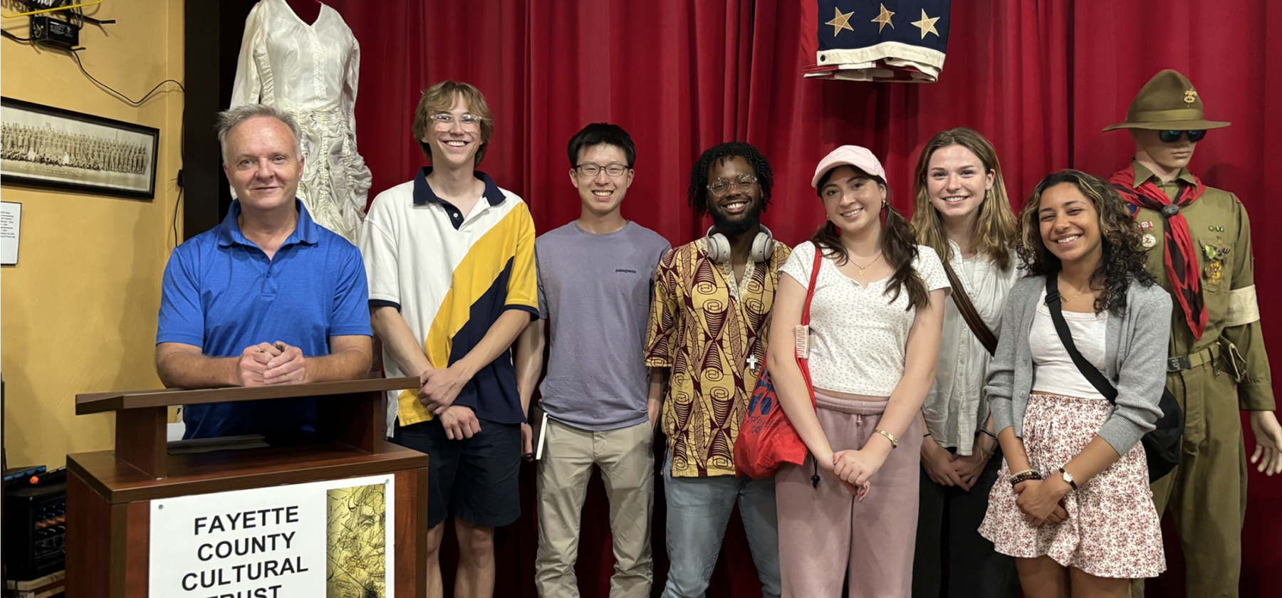 Group photo of students with director of museum smiling for camera