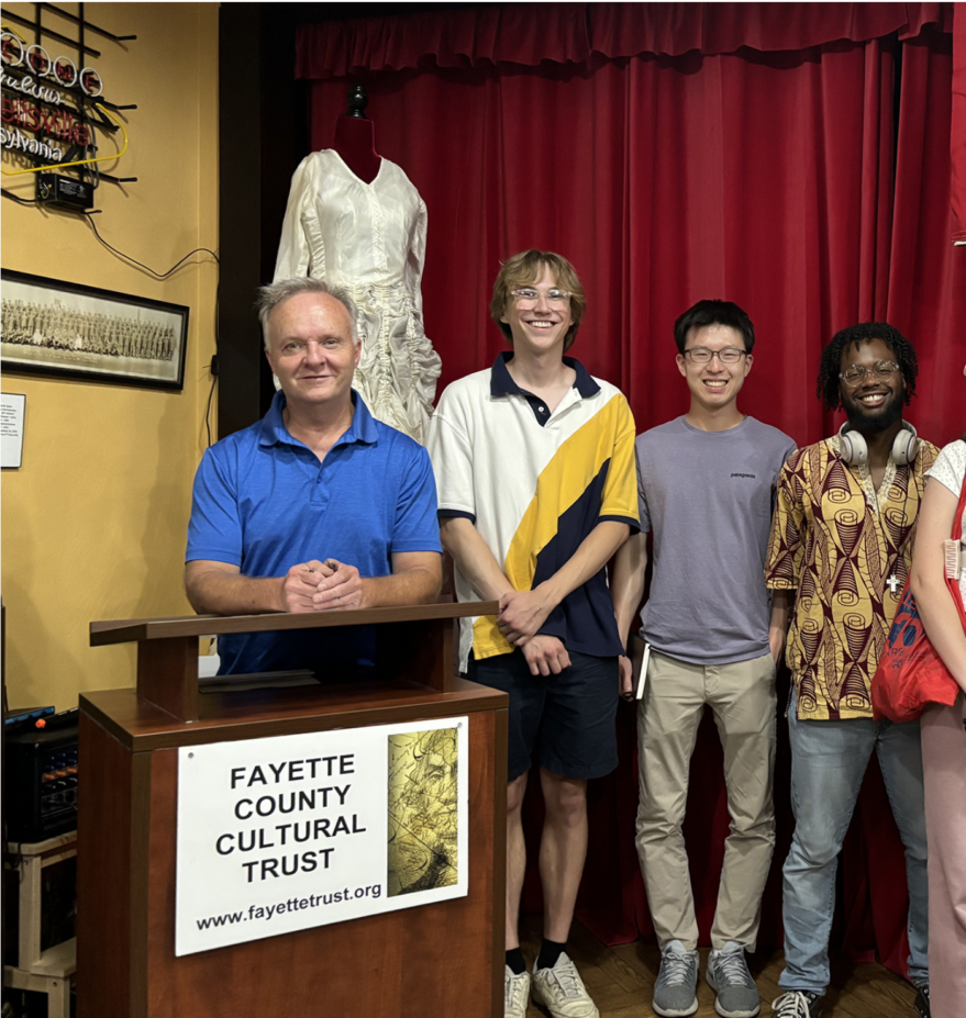 Group photo of students with director of museum smiling for camera