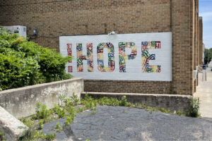 Side of brick building with a mural with the word hope