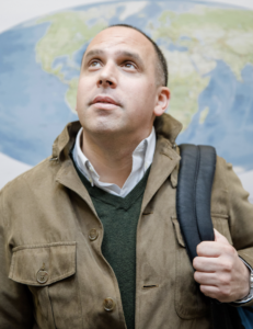 Headshot of documentarian looking up with a map behind him.