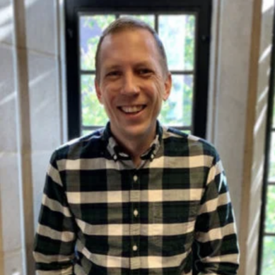 headshot of instructor Steve Kocher, male with light skin and short brown hair wearing wearing black and white plaid shirt in front of a window