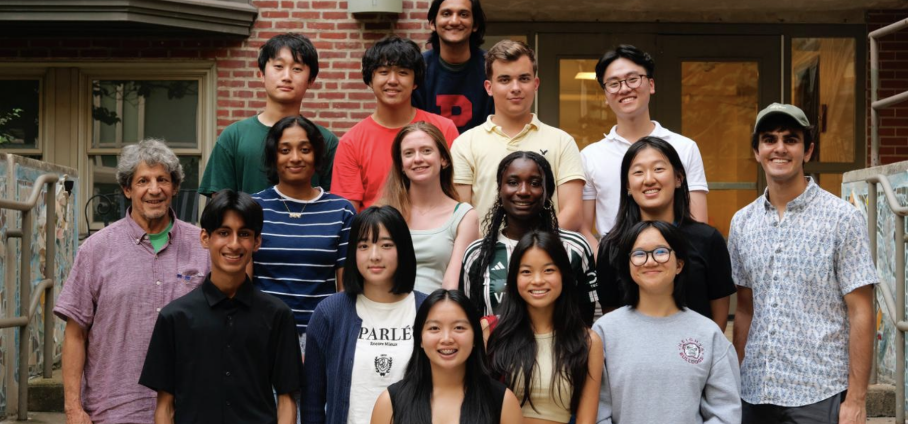 group photo of students smiling for camera in front of their college residence