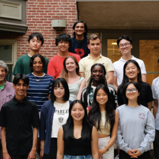 group photo of students smiling for camera in front of their college residence