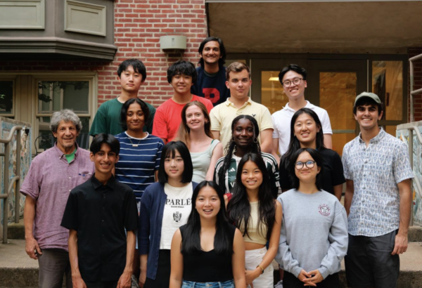 group photo of students smiling for camera in front of their college residence