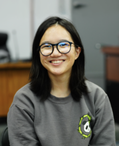 Headshot of woman with shoulder length dark hair and wearing glasses and a gray sweatshirt