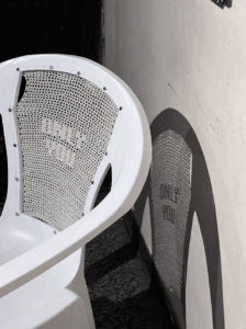 Artwork with white plastic chair against a wall with shadow