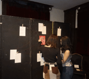 Two students looking artwork taped to wall.
