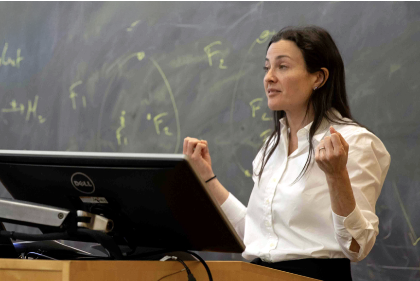 Female professor standing in front of a chalkboard teaching a lesson