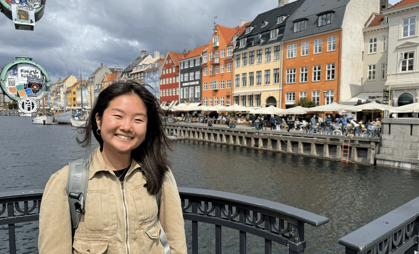 author in front of scenic background with water and buildings.