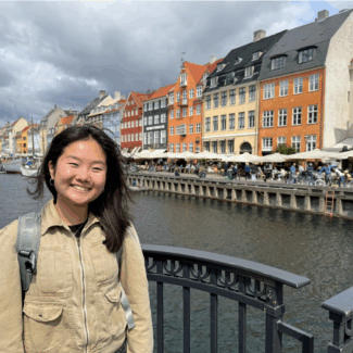 author in front of scenic background with water and buildings.