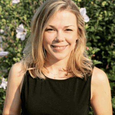 woman with light skin, shoulder-length blonde hair wearing a sleeveless black top