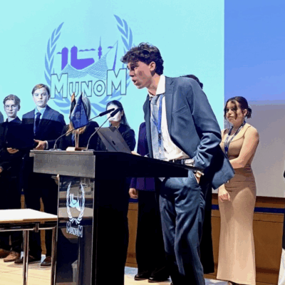 SNF Paideia Fellow standing at podium wearing a blue suit.