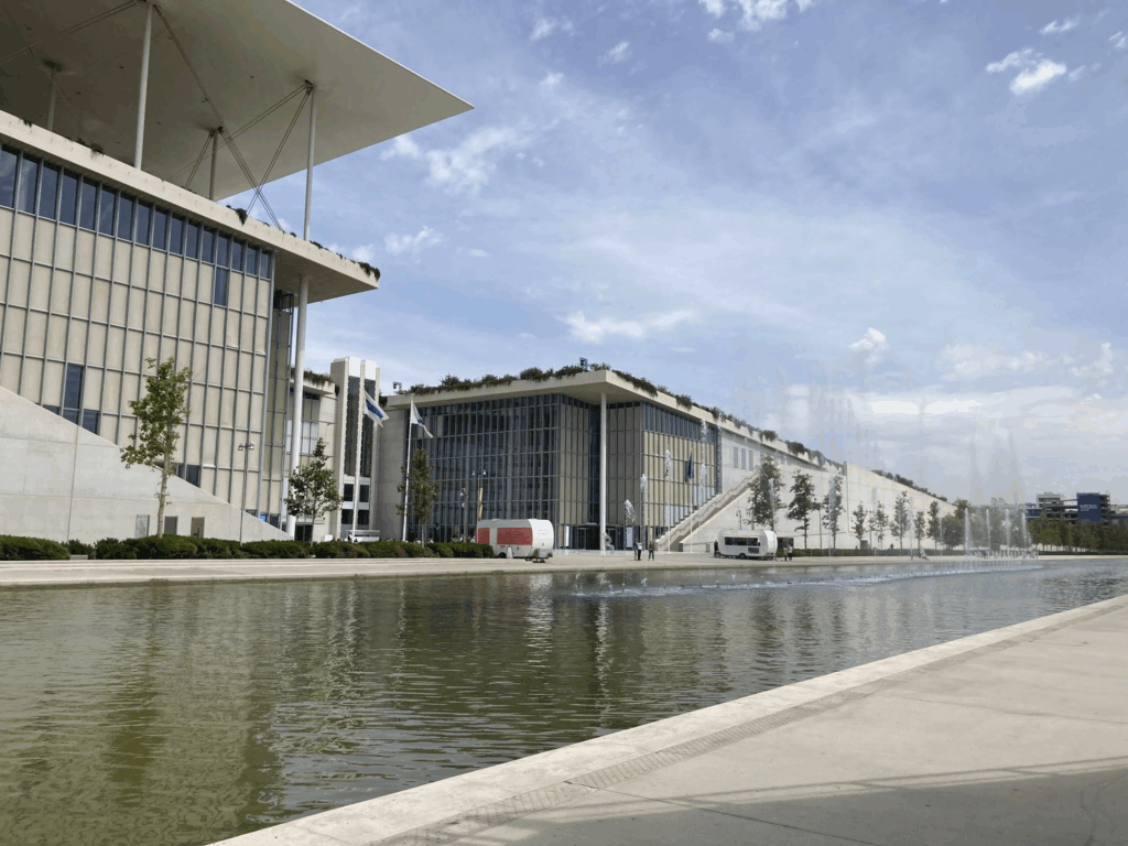 modern buildings that are part of the SNF Cultural Center in Greece beside a large long fountain