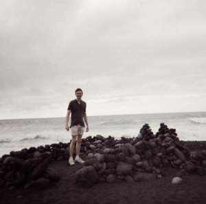 photos of alumni Isaac Gatena by the water near rocks.